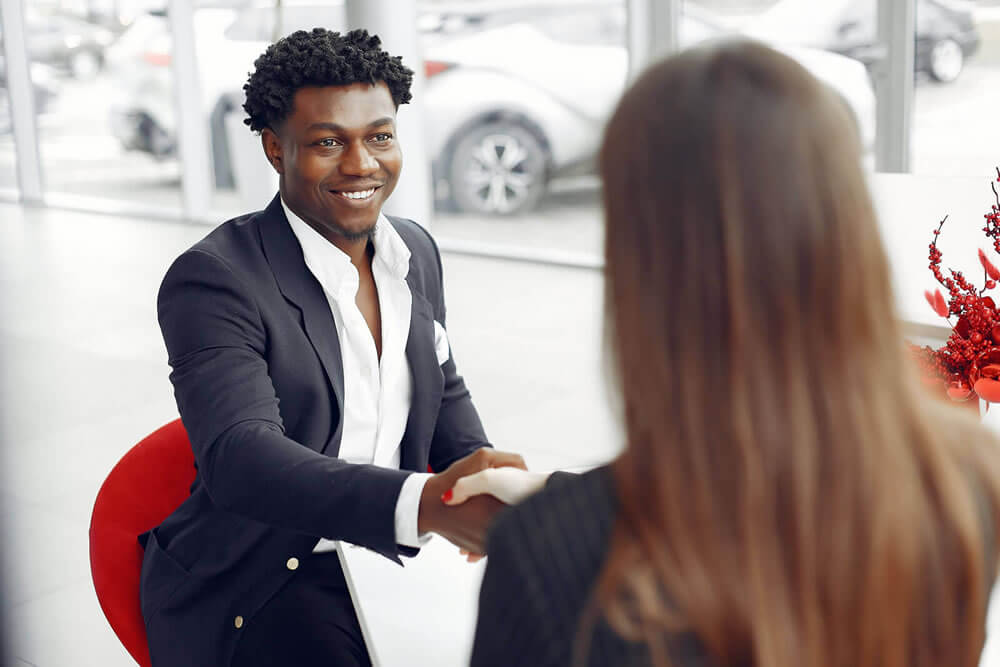 A man shaking hands with a car salesman